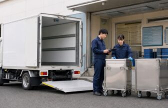 学校給食センターの搬入口で求人条件と配送設備を確認する二人の配送スタッフ